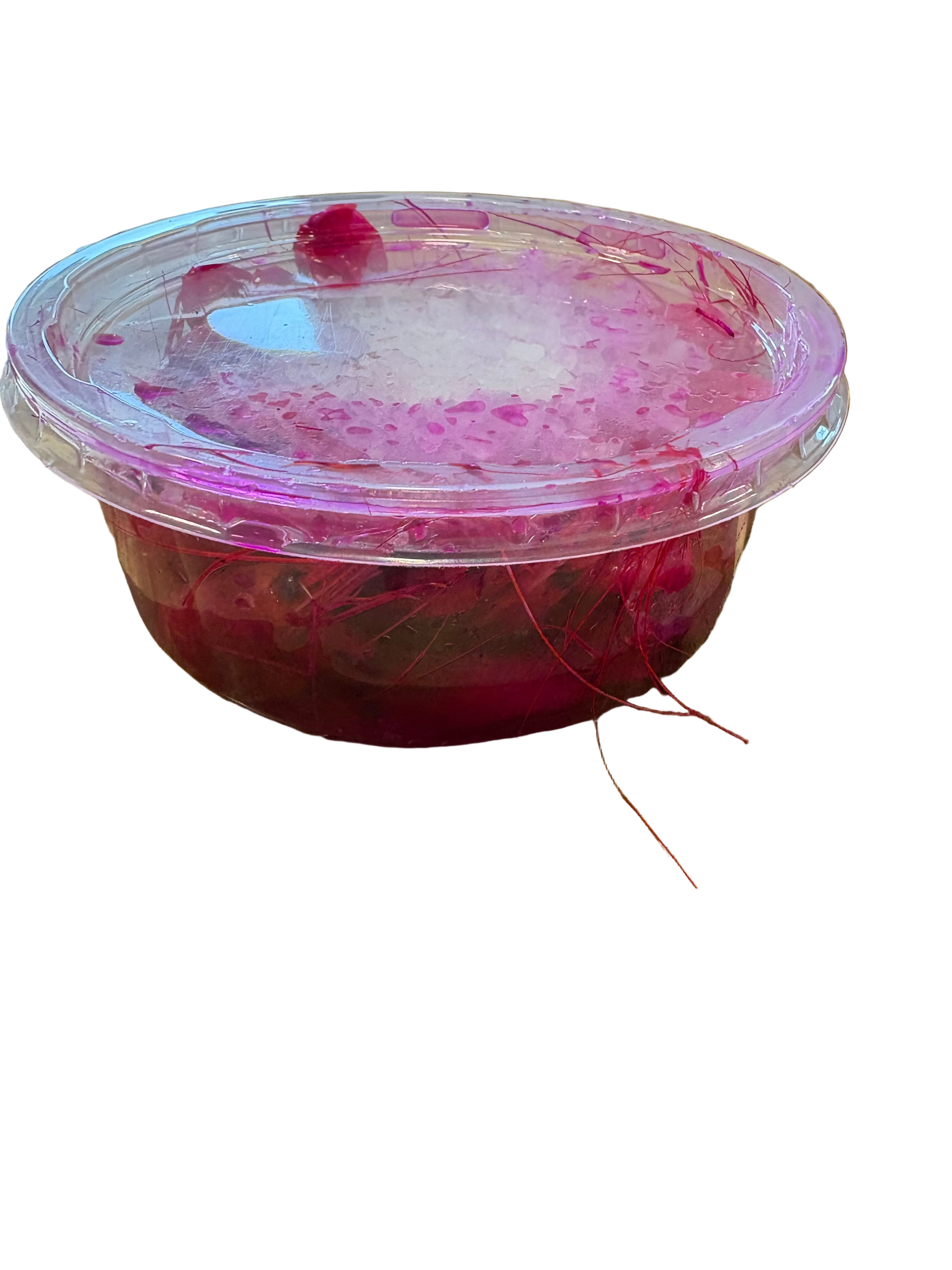 Pink container with a red substance on a wooden surface