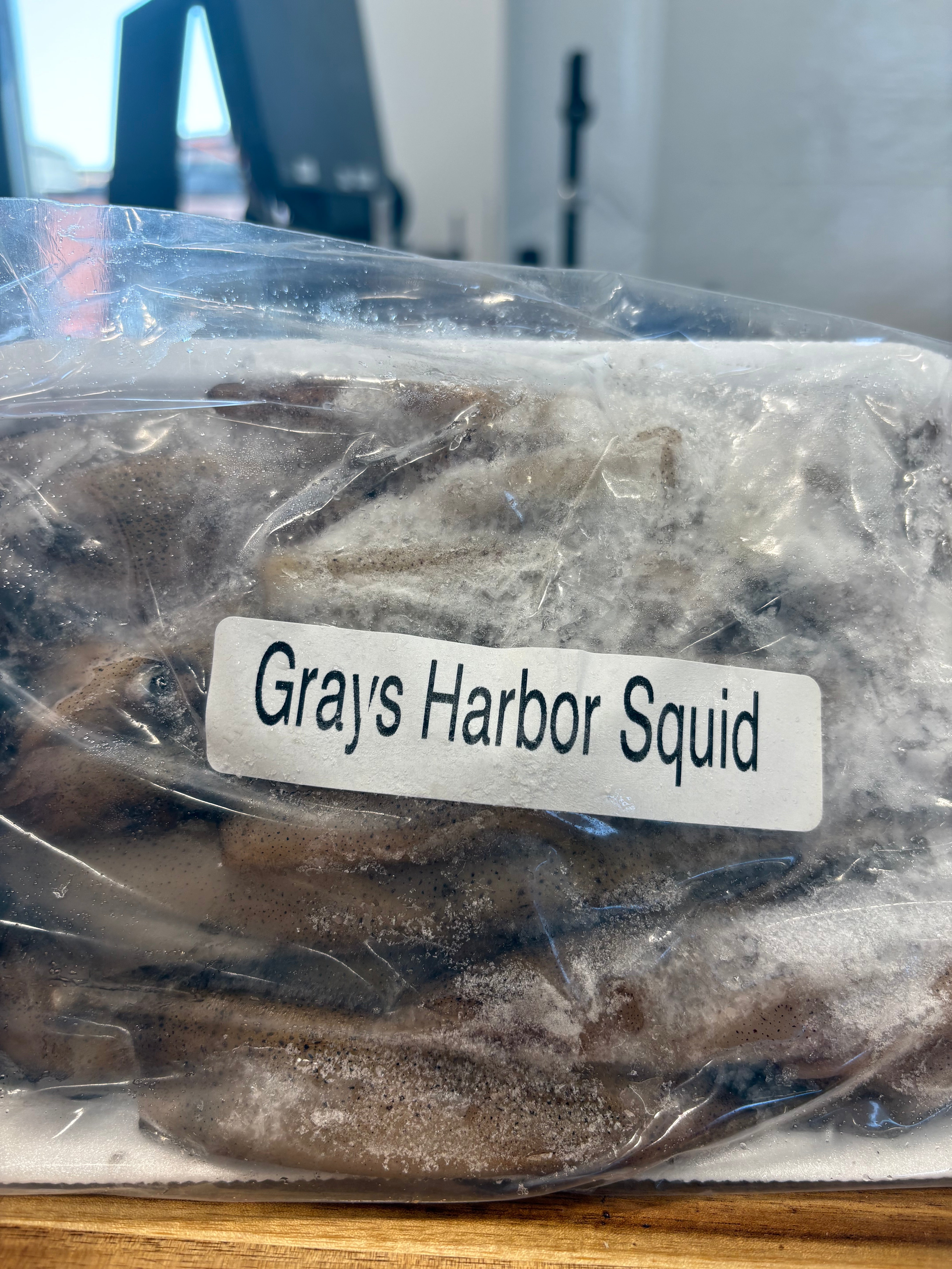 Packaged Grays Harbor Squid with a label on a wooden surface
